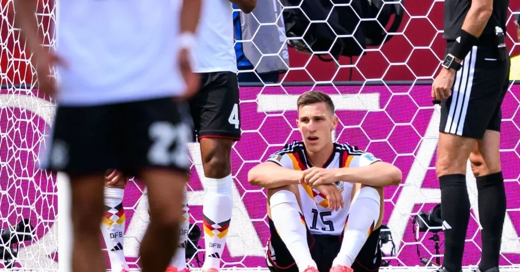 Nico Schlotterbeck saindo do campo segurando o tornozelo com a camisa da seleção da Alemanha