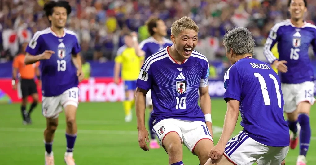 Bandeiras do Brasil e do Japão ao lado de uma bola de futebol em estádio