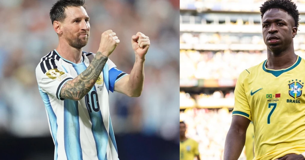 Jogadores em campo durante jogo entre seleções, torcedores nas arquibancadas ao fundo