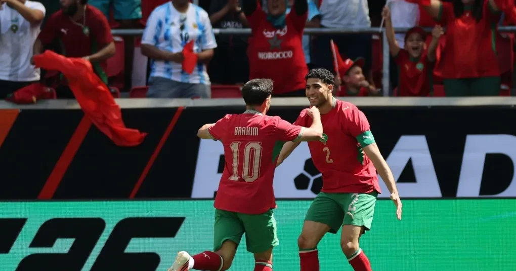 Jogadores da seleção de Marrocos em treino com bola e banco de reservas ao fundo