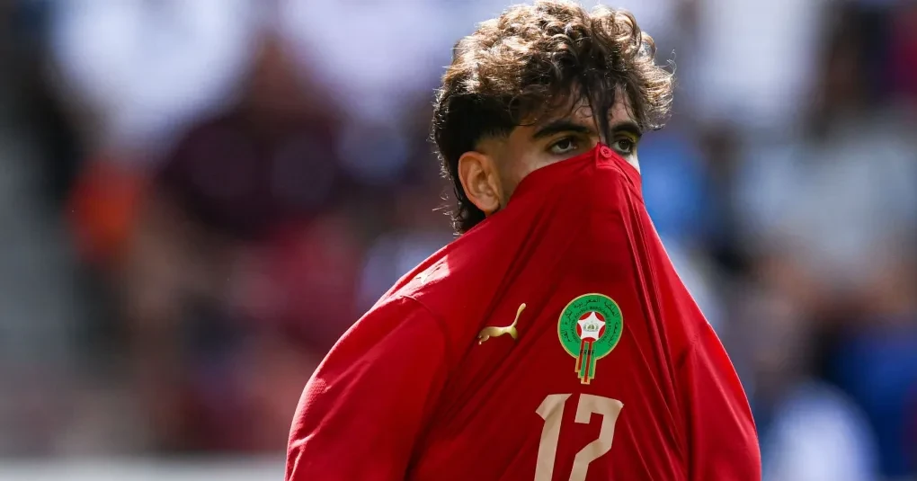 Jogadores marroquinos em treinamento com bandeira do Marrocos ao fundo