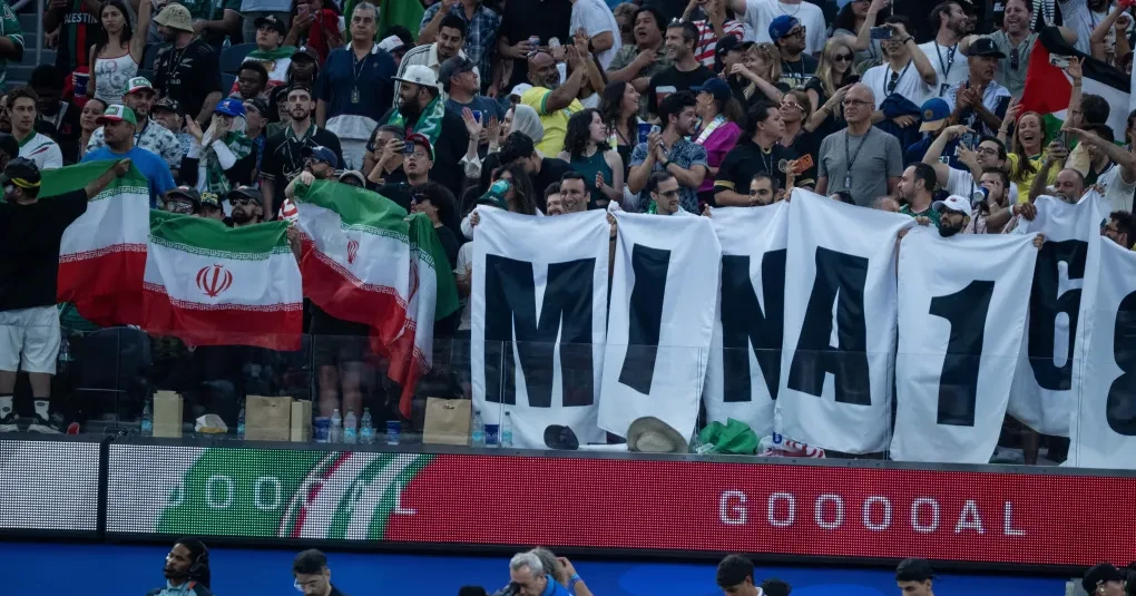 Torcedores iranianos no SoFi Stadium com bandeiras e cartazes de protesto e apoio