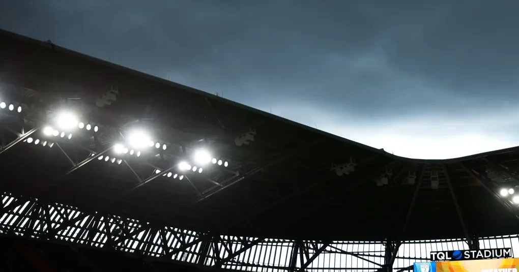 Painel meteorológico e estádio com nuvens escuras ao fundo