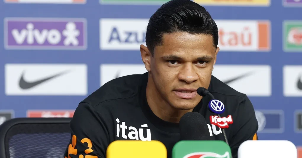 Douglas Santos falando em coletiva com a camisa da Seleção Brasileira