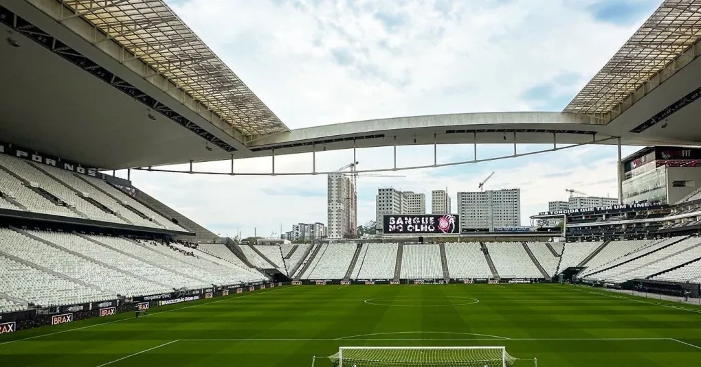 Torcedores reunidos trocando figurinhas em mesas dentro de área temática de estádio
