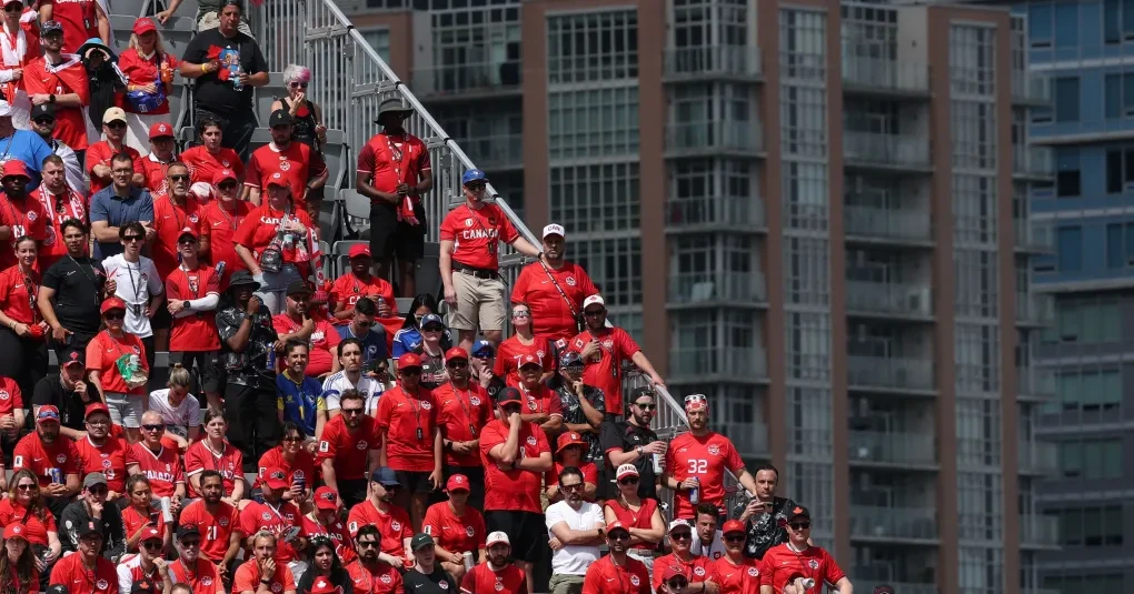 Torcida canadense vestida de vermelho em rua com bandeiras, apoiando a seleção
