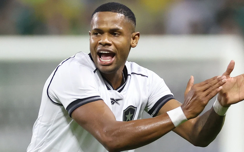 Júnior Santos disputando bola contra jogador do Palmeiras em campo