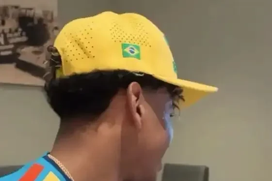 Lamine Yamal sentado usando boné amarelo com a bandeira do Brasil