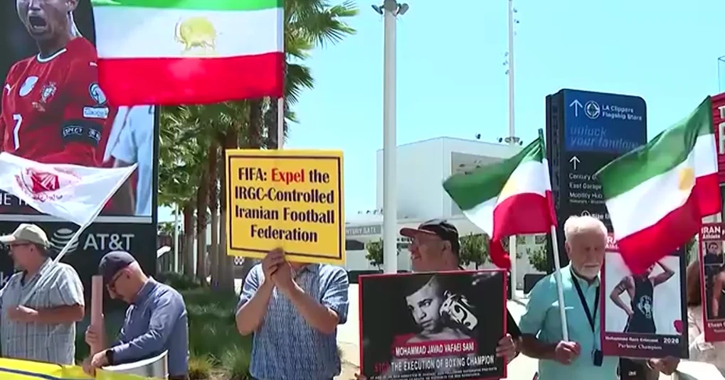 Manifestantes iraniano-americanos com bandeiras e cartazes perto de um estádio em Los Angeles