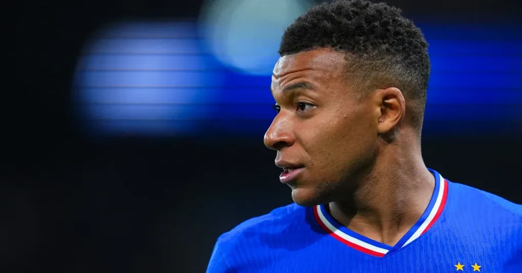 Kylian Mbappé falando em entrevista, microfones à frente