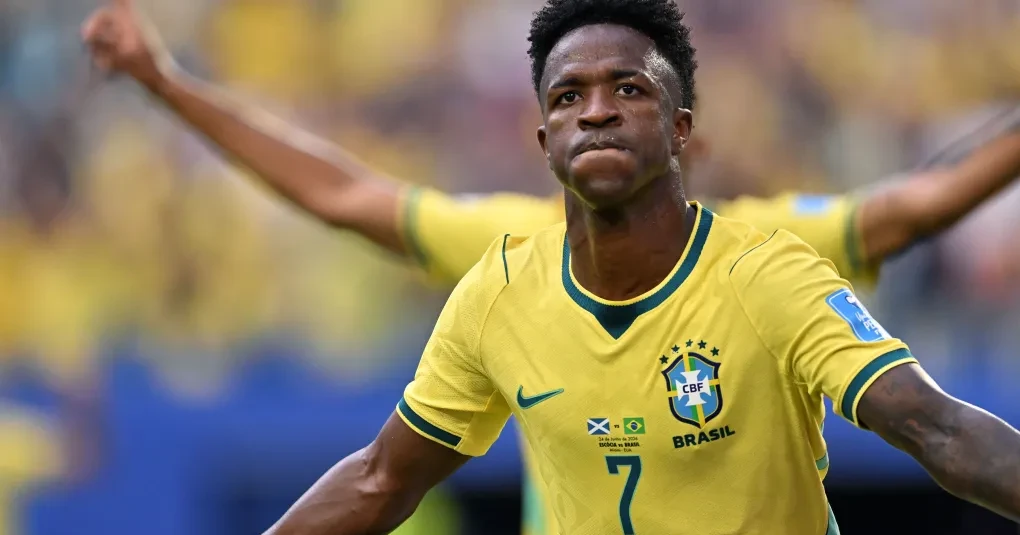 Vinicius Júnior comemorando com a camisa da seleção brasileira no gramado