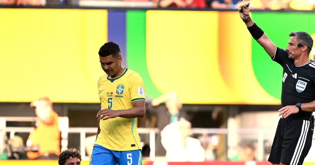 Árbitro mostrando cartão amarelo a jogador durante partida de futebol