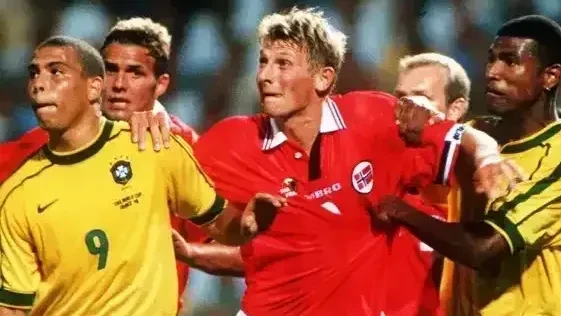 Bandeiras da Noruega e do Brasil tremulando em estádio antes da partida