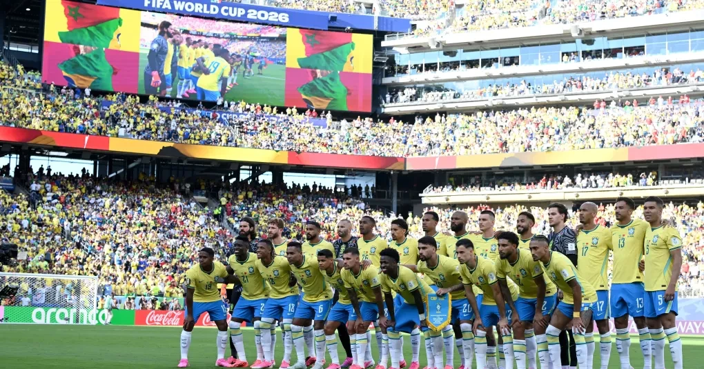 Torcida brasileira com camisas e bandeiras em estádio durante jogo internacional