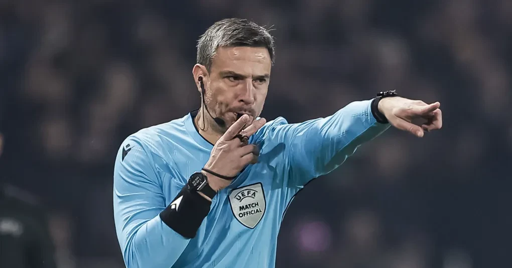 Árbitro Slavko Vincic com apito e uniforme em campo durante partida