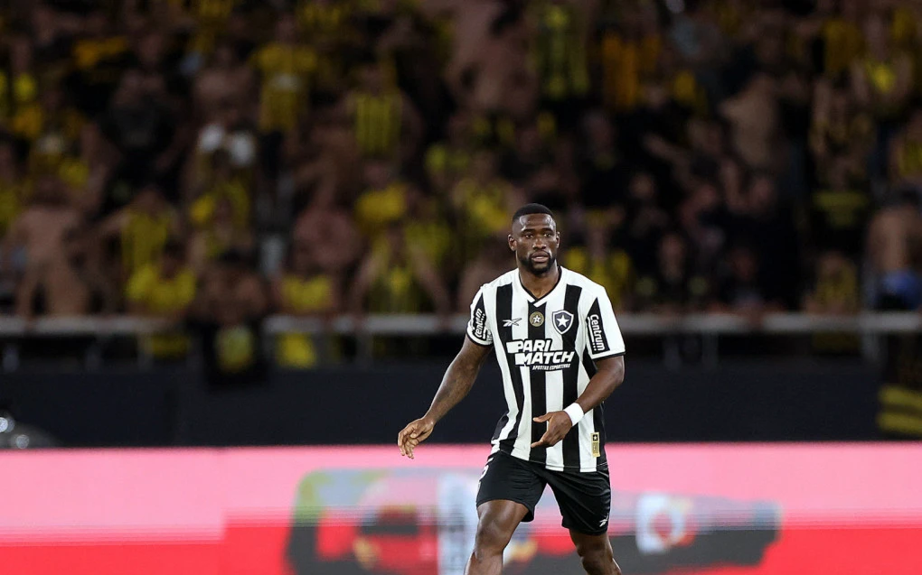 Bastos disputando lance pelo Botafogo com estádio ao fundo