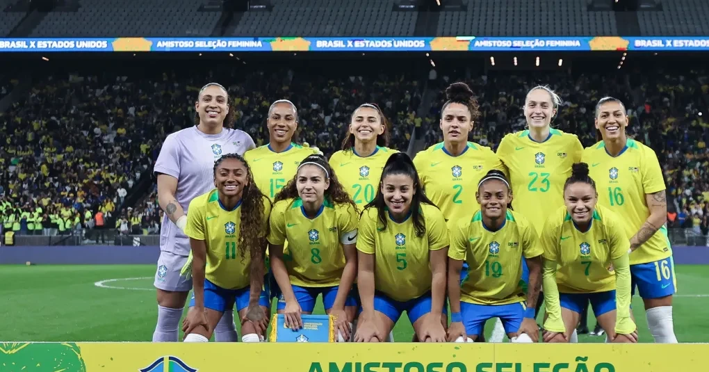 Torcida feminina em estádio com bandeiras e arquibancada cheia