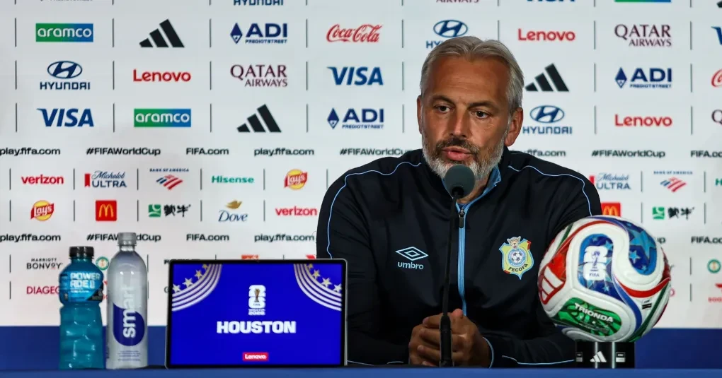 Sébastien Desabre em coletiva de imprensa, expressão séria e microfones à frente