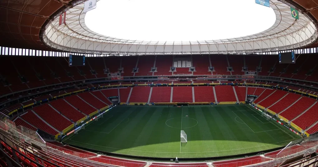 Jogadores do Flamengo aquecendo no gramado com bandeiras rubro-negras ao fundo