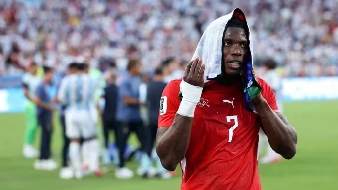 Breel Embolo caído na lateral do campo sendo observado pela arbitragem durante revisão do VAR