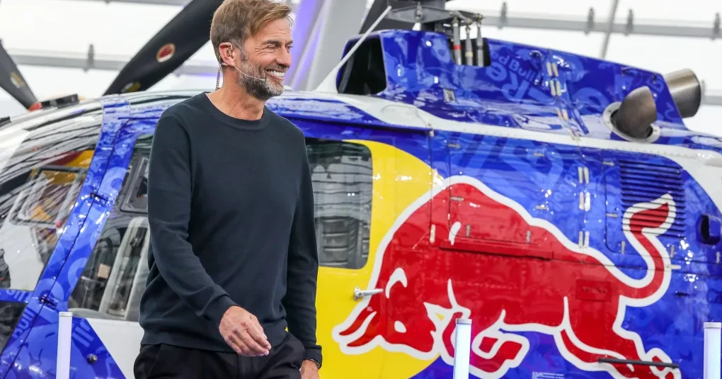 Jürgen Klopp sorrindo durante entrevista com microfones ao fundo