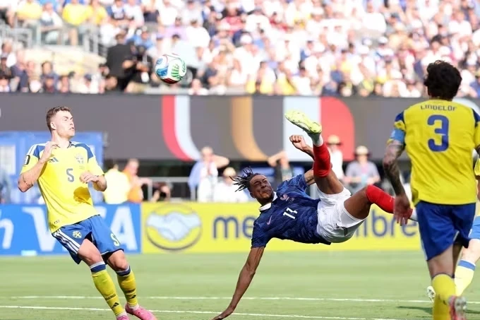 Michael Olise em ação com a camisa da seleção francesa, executando passe em jogo