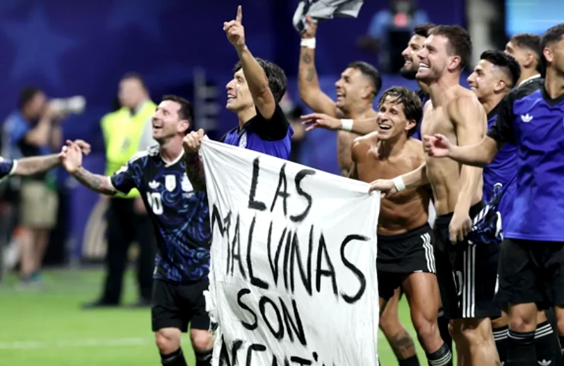 Jogadores argentinos no gramado exibindo faixa com a frase 'As Malvinas são argentinas'
