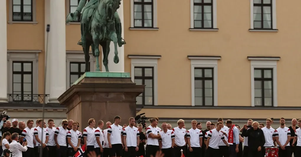 Multidão com bandeiras norueguesas na Karl Johans gate durante recepção à seleção