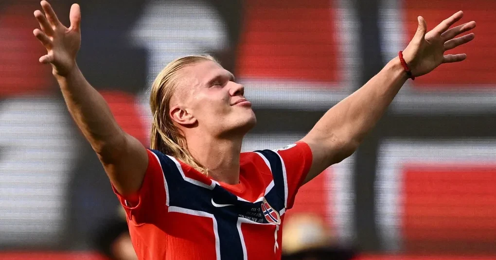 Erling Haaland com a camisa da seleção da Noruega comemorando em campo