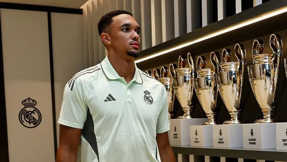 Trent Alexander-Arnold em entrevista com o emblema do Real Madrid ao fundo