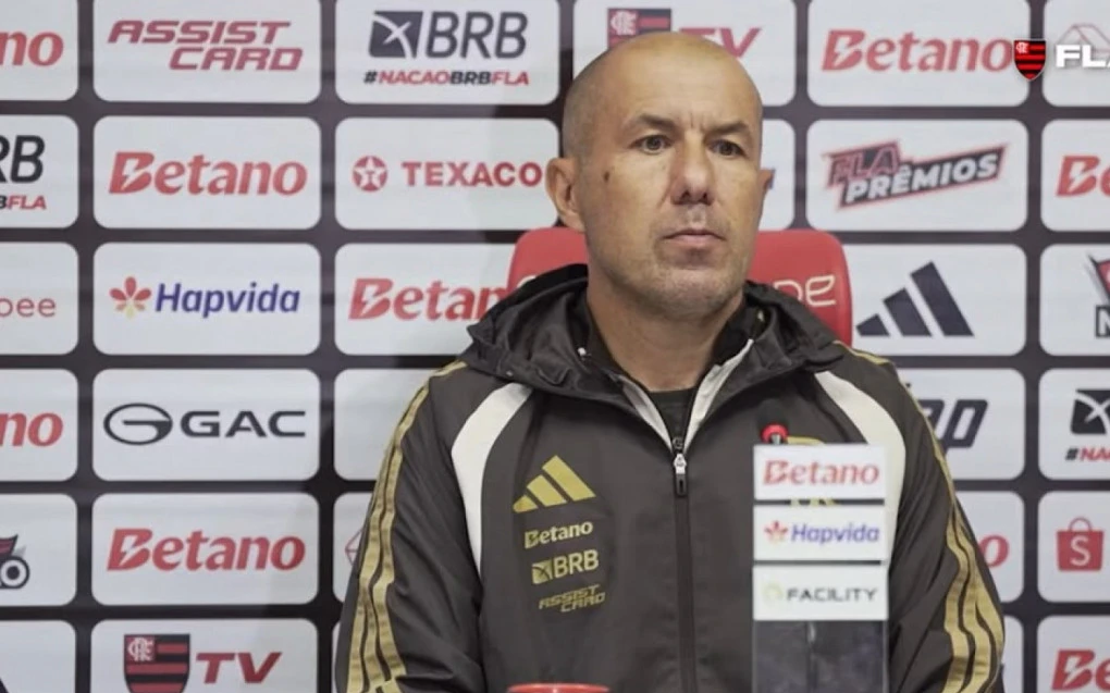 Leonardo Jardim em entrevista coletiva com microfone e painel de fundo do Flamengo
