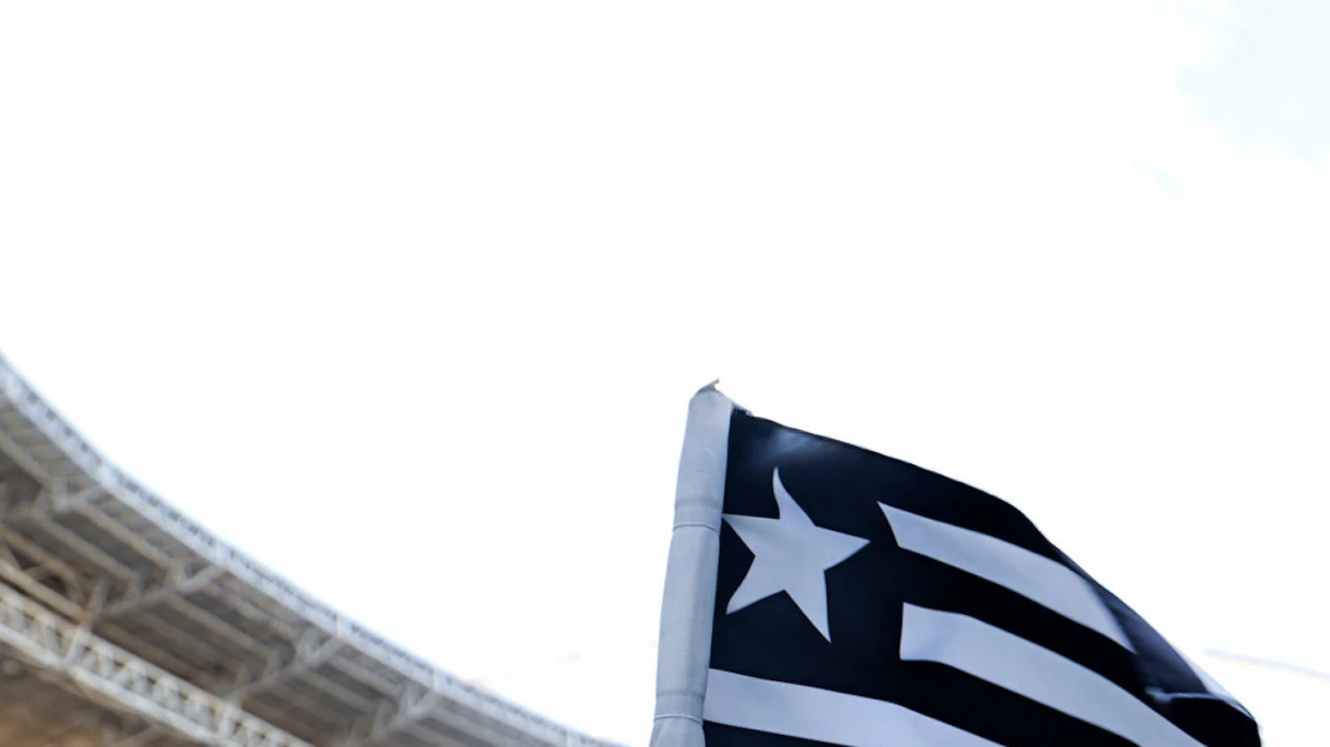 Bandeira do Botafogo tremulando no Estádio Nilton Santos, com arquibancada ao fundo