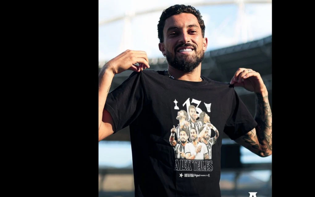 Alex Telles segurando várias camisas especiais do Botafogo durante evento