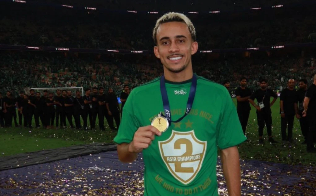 Matheus Gonçalves segurando o troféu da Liga dos Campeões Asiática com camisa do Al Ahli