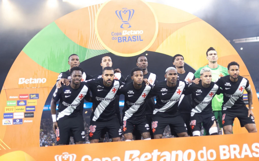 Jogadores do Vasco comemorando em campo com torcida ao fundo em São Januário
