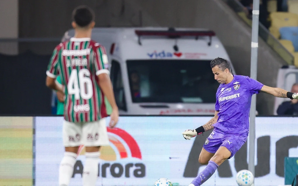Fábio ajoelhado comemorando com luvas e uniforme do Fluminense
