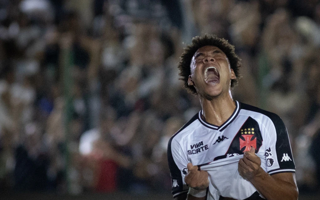 Jogador do Vasco comemorando gol, braços erguidos no gramado